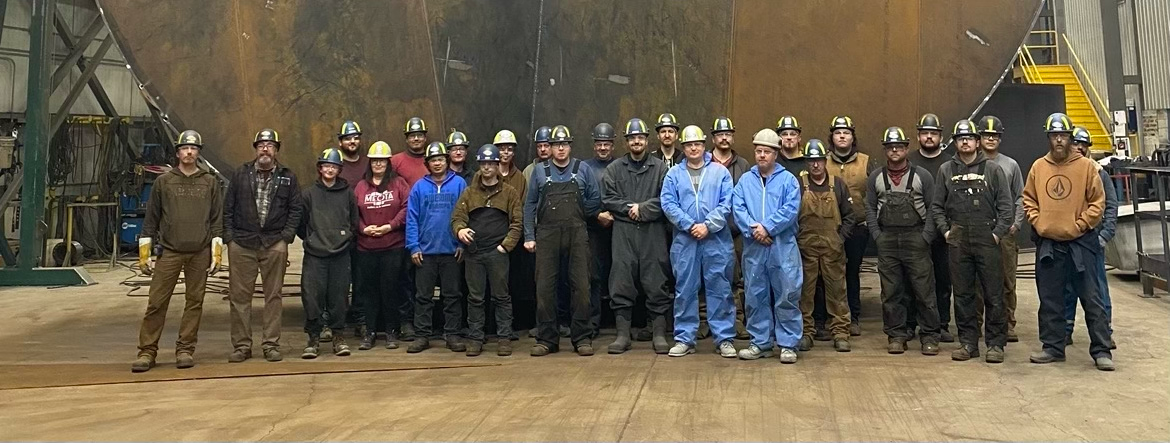 Battleford Team Standing Proudly in Front of a 35' Diameter Steel Storage Tank, Highlighting LMG's Expertise in Custom Tank Solutions